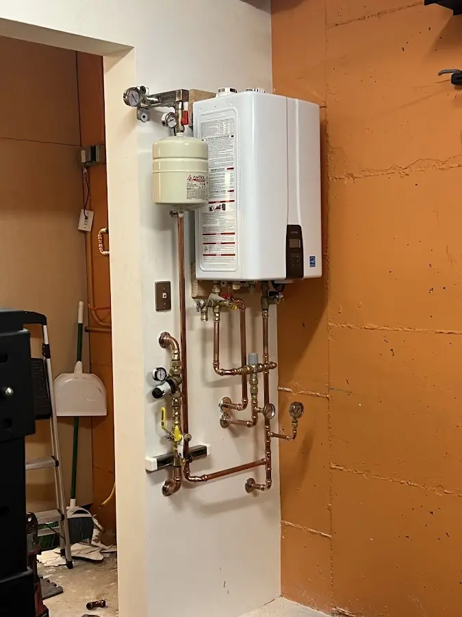 Plumbing technician inspecting water heater connections in Clayton